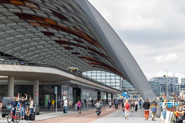 The the roof of concourse behind Amsterdam's Centraal station sweeps down to the Ij. Pedestrians and the inevitable cyclists share the space teeming with life